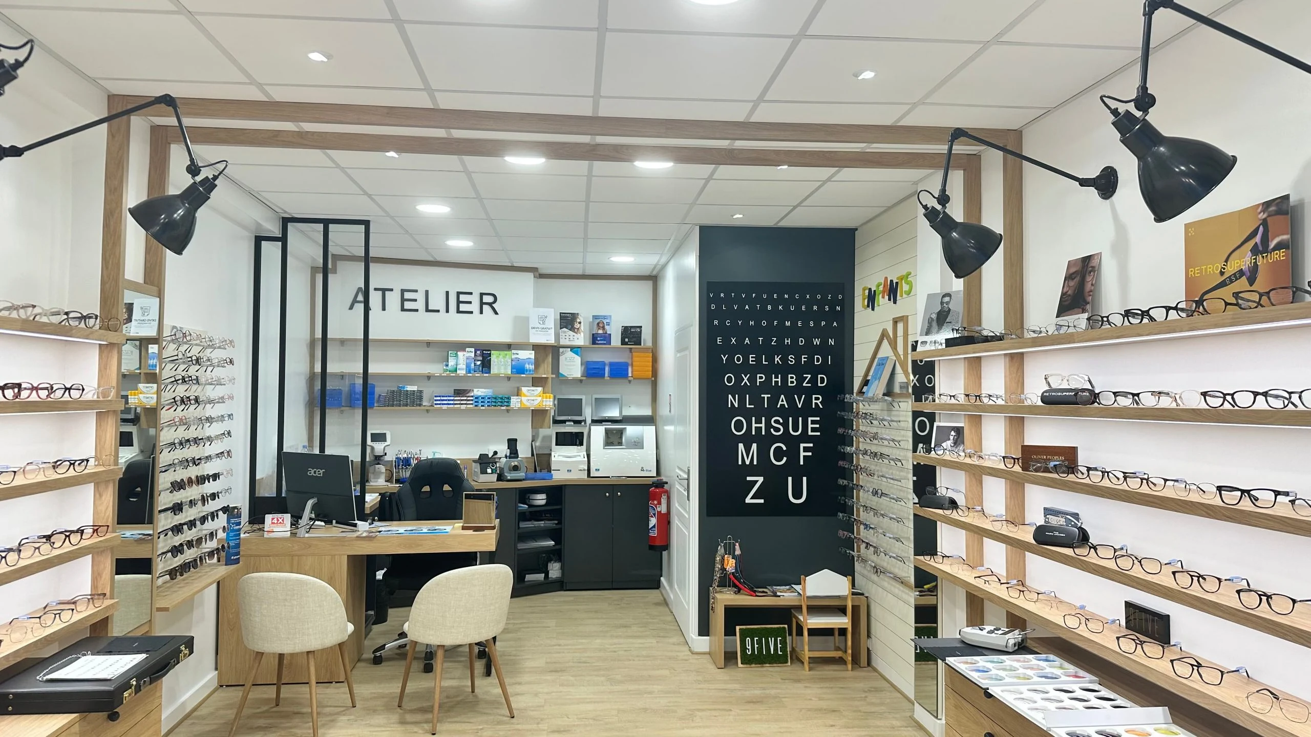 Intérieur réel de Coty Optique : bureau et atelier à gauche, tableau de contrôle visuel au fond et montures à droite